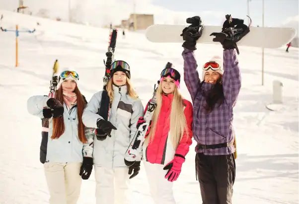 Friends raising skis and snowboards on a ski slope