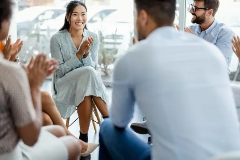 Group applauding a smiling woman during a session