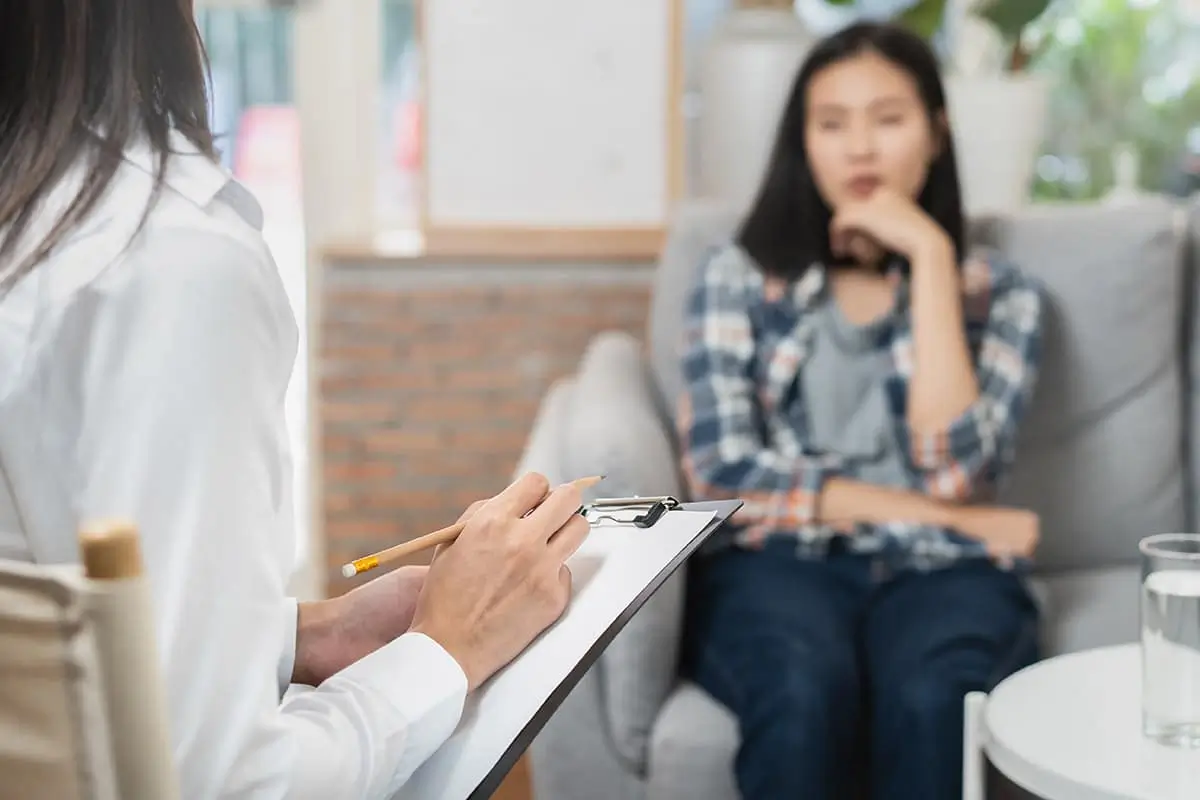 Counselor with a clipboard talking with a young woman