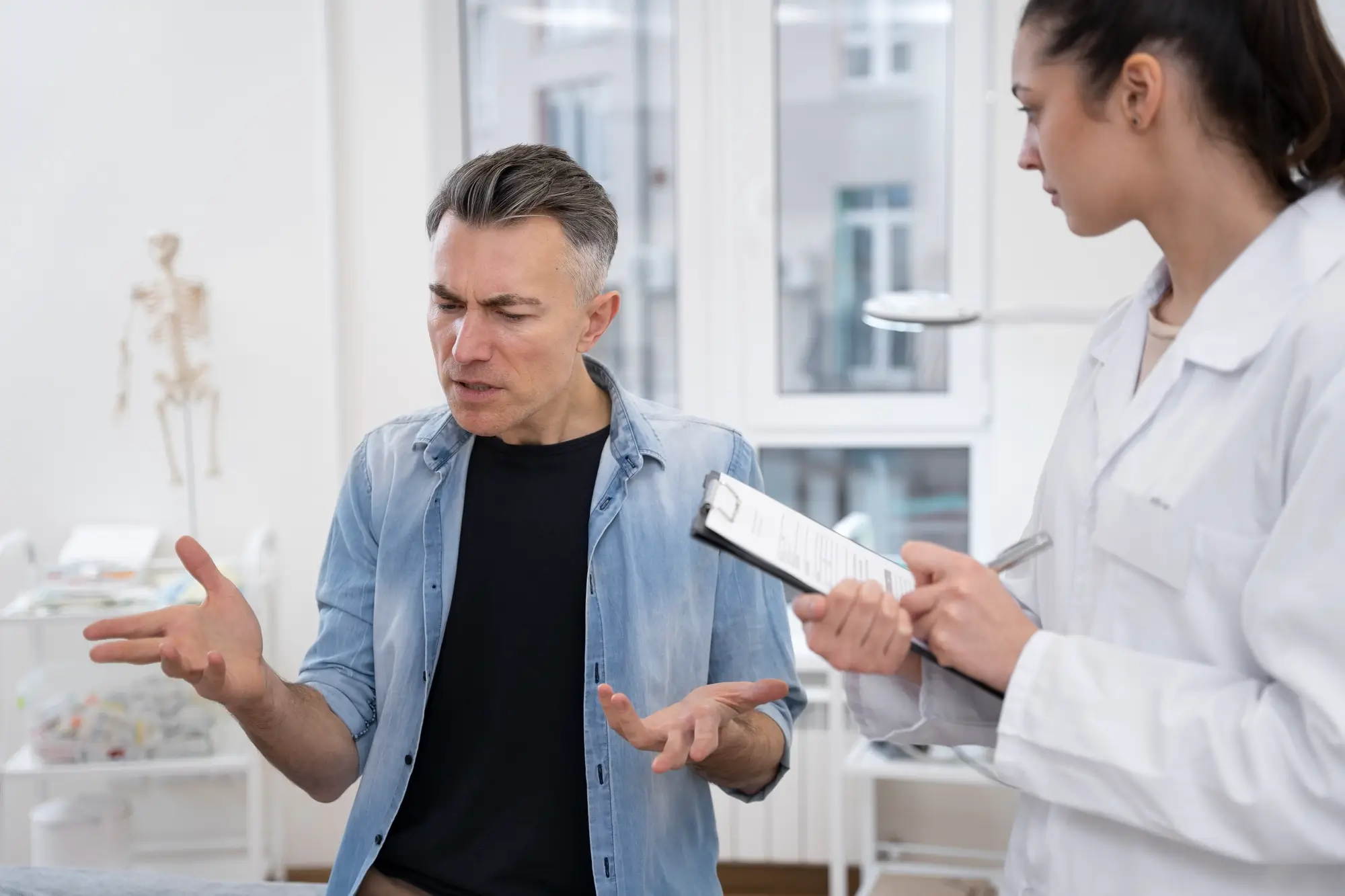 Doctor reviewing notes with a frustrated man