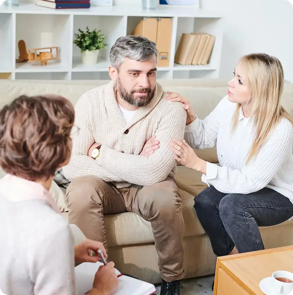 Friends comforting a man with crossed arms