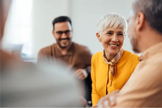 Smiling adults in conversation at a support meeting