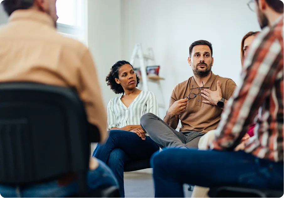 Man speaking to members of a group therapy circle