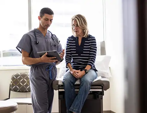 Nurse showing a tablet to a seated patient