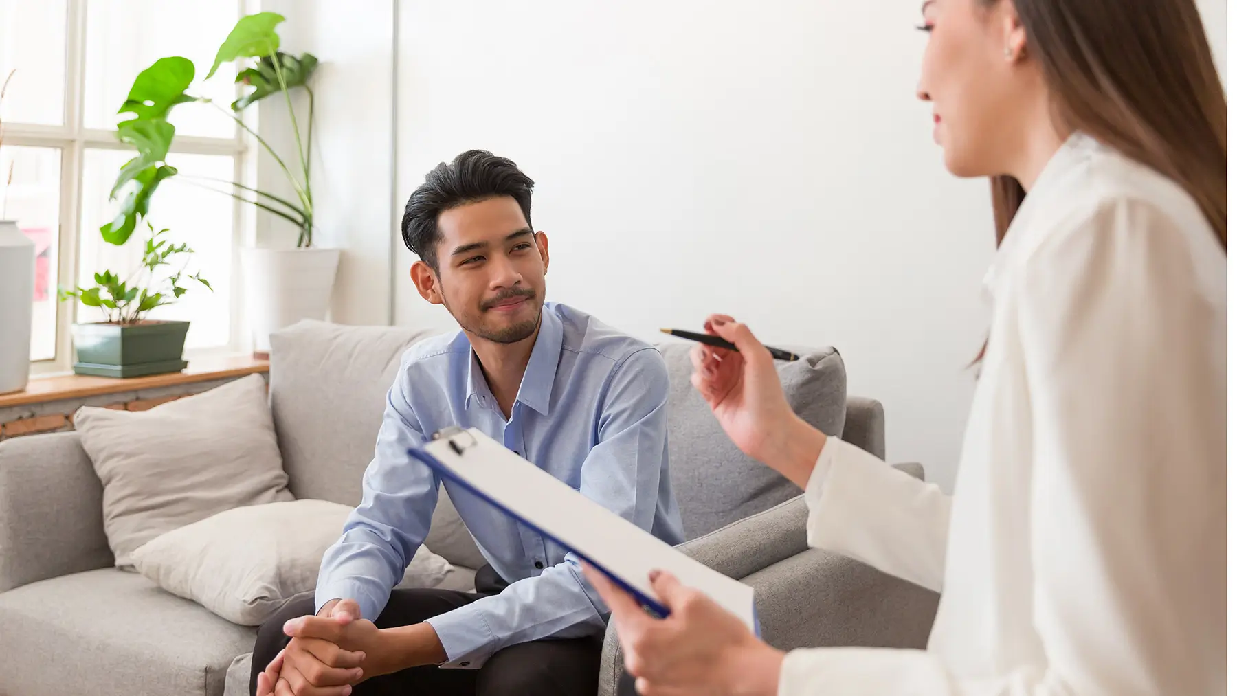 Therapist with a clipboard talking with a young man
