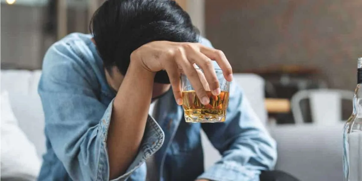 Man holding a glass of alcohol with his head down