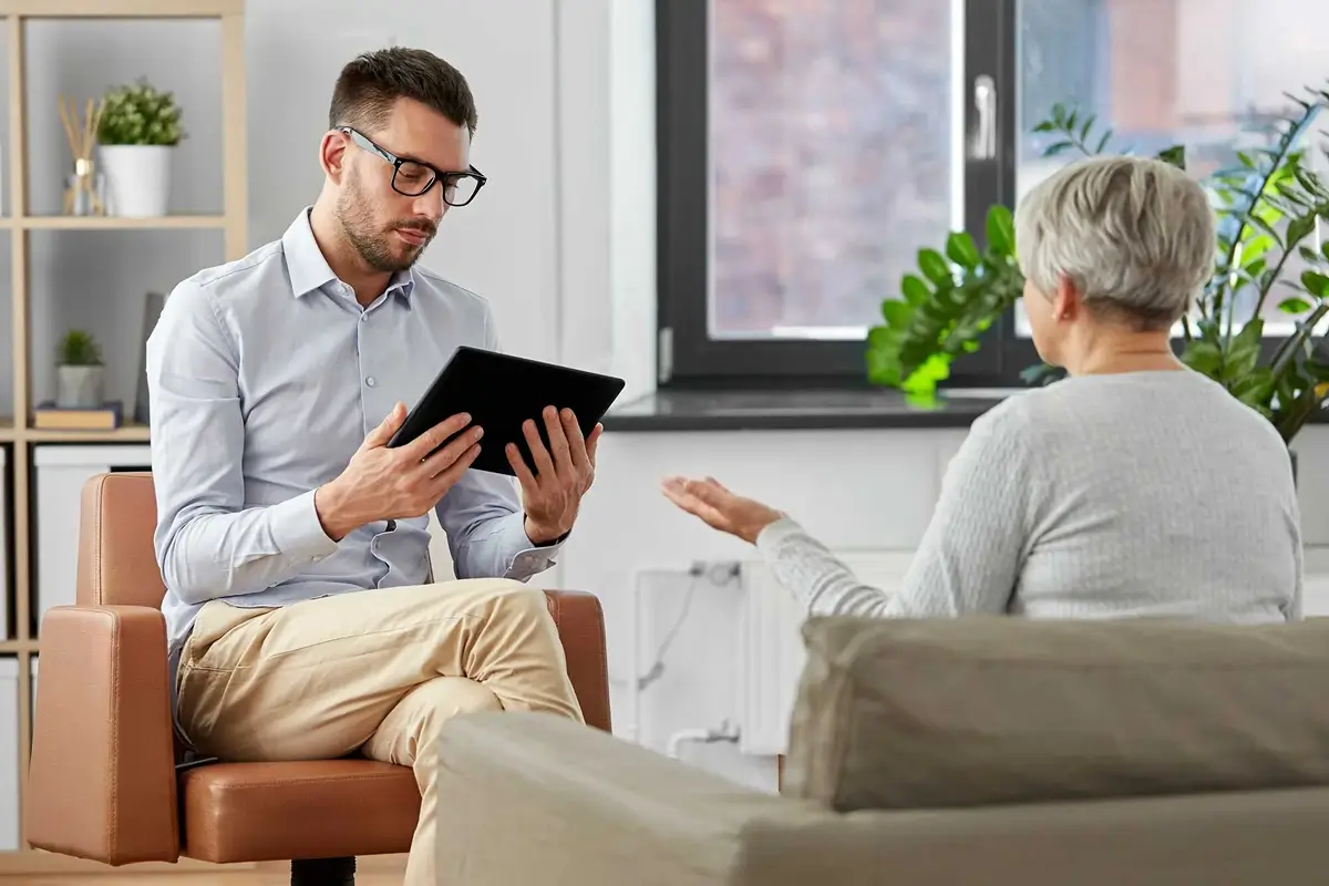 Counselor with a tablet talking with an older woman