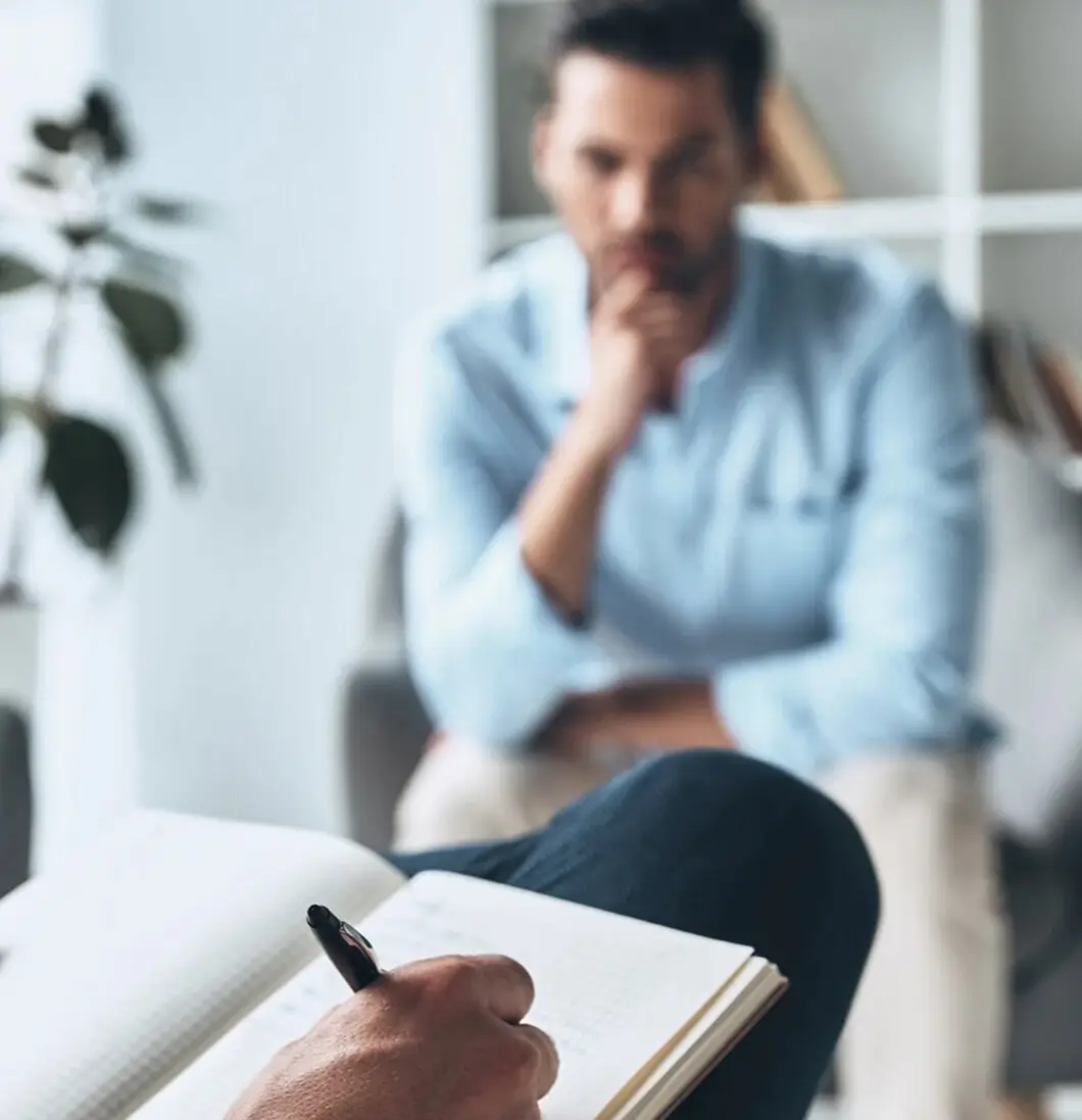Pensive man listening while a counselor takes notes