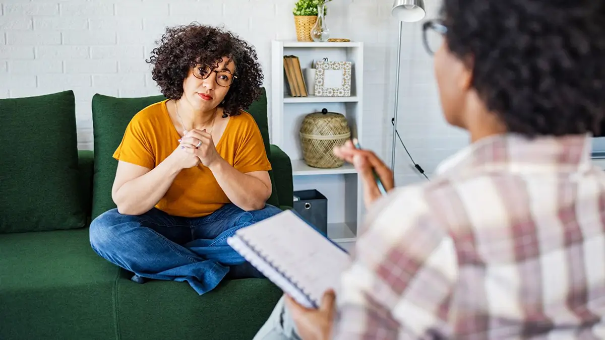 Counselor reading notes to a woman seated on a green couch