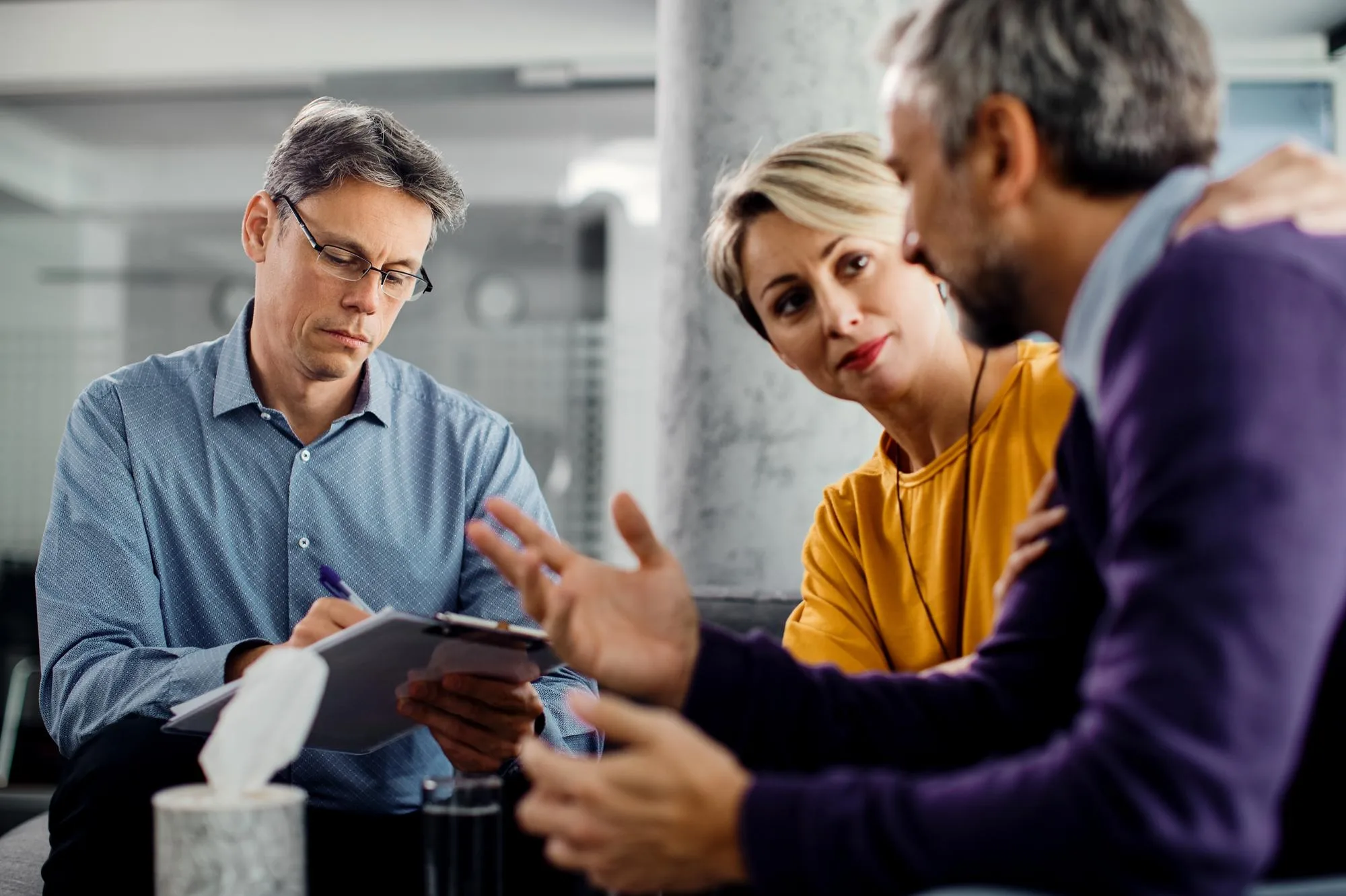 Couple talking with a therapist who is taking notes
