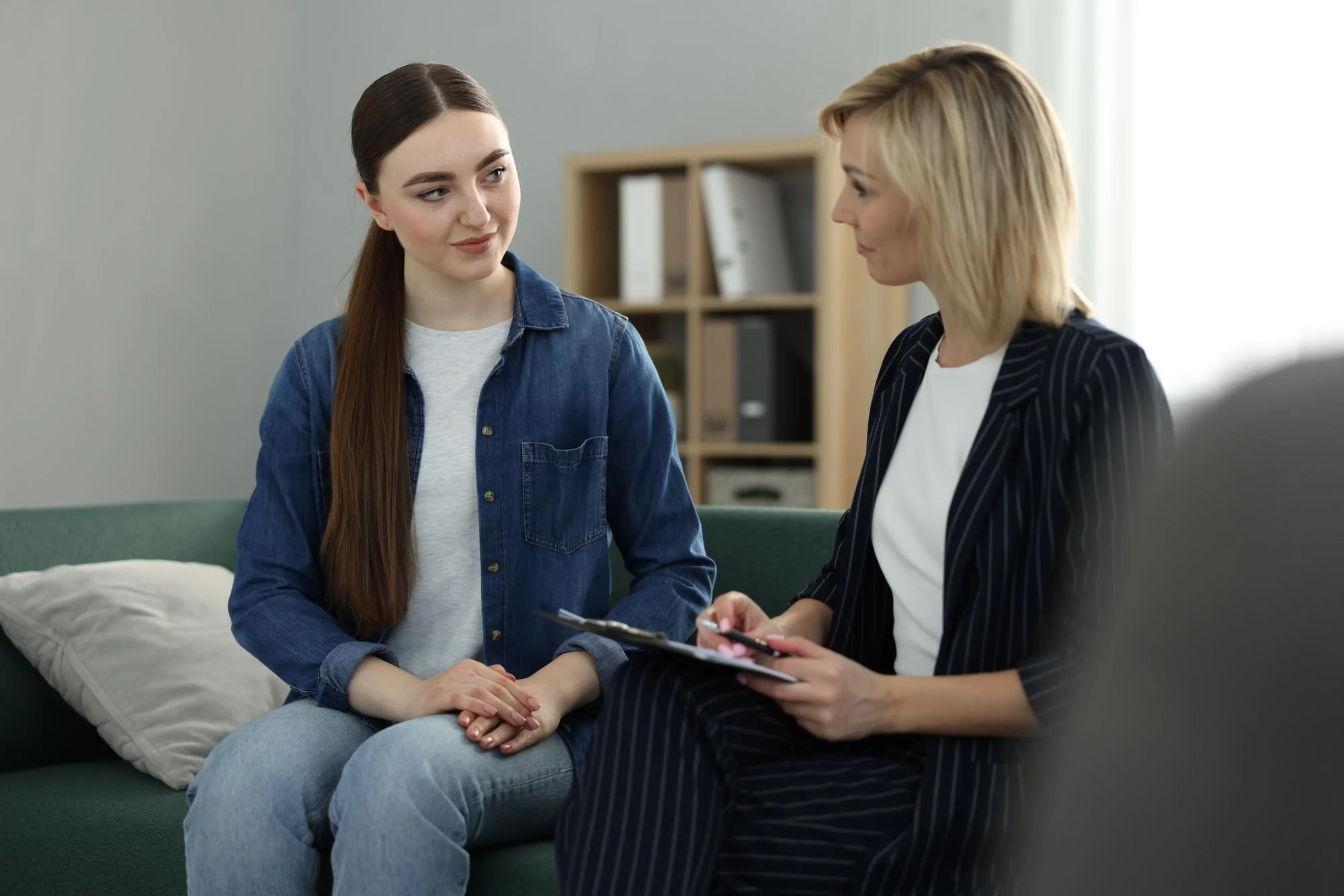 Young woman talking with a counselor holding a tablet