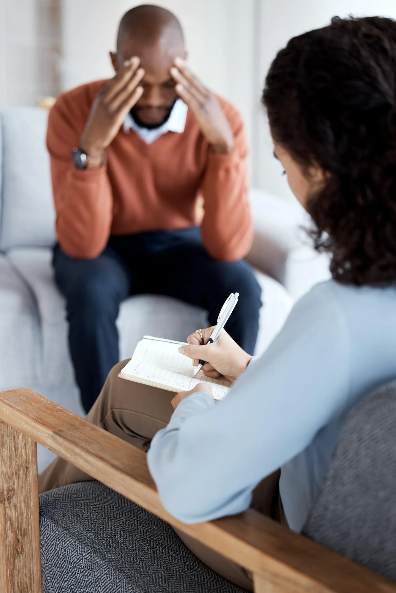 Man holding his head while talking with a counselor