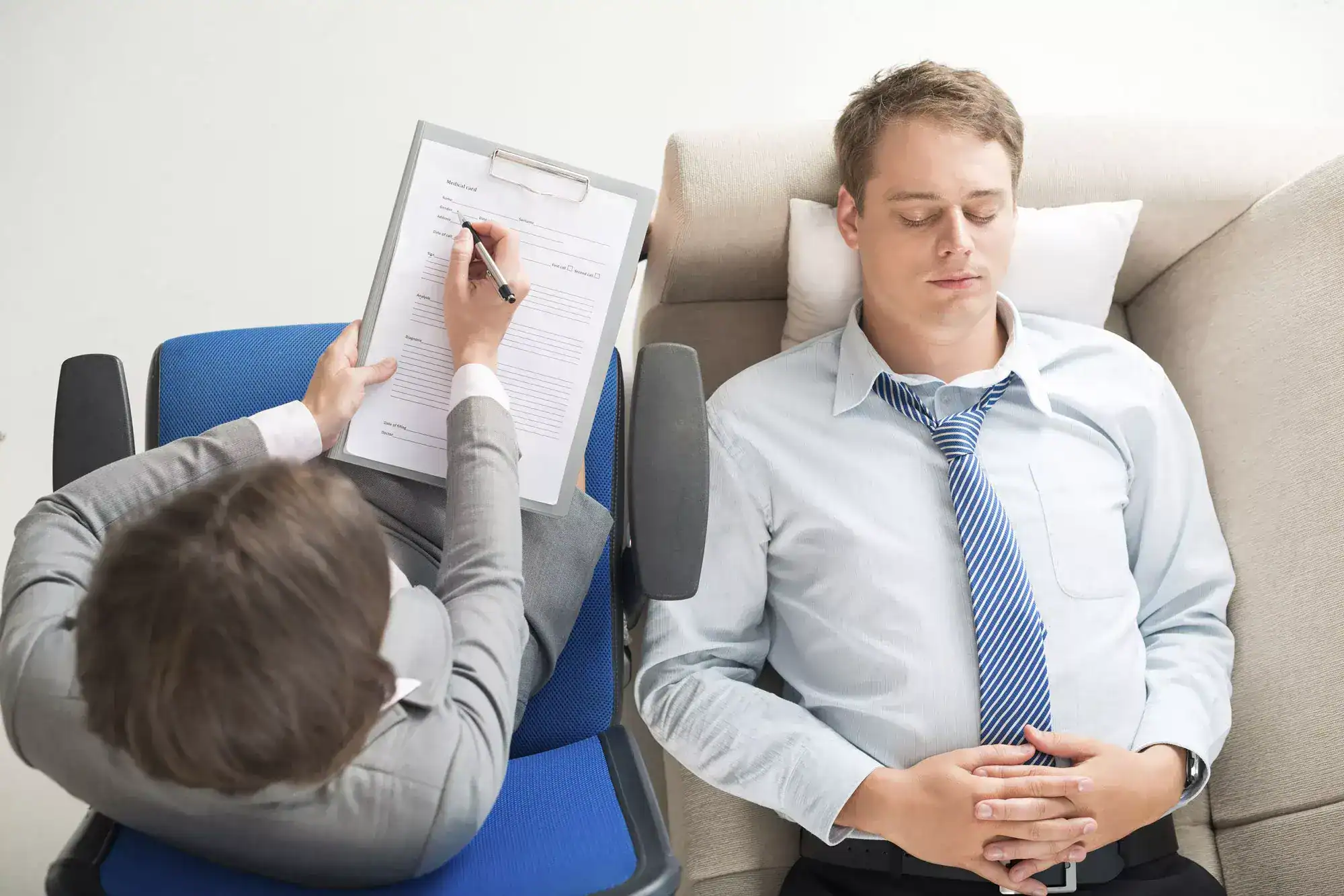 Therapist writing notes while a man rests on a recliner