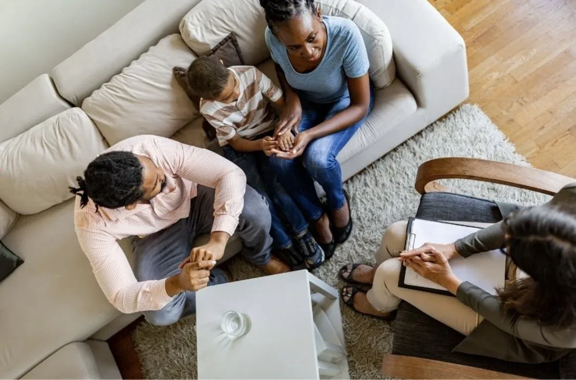 Overhead view of a family talking with a counselor at home