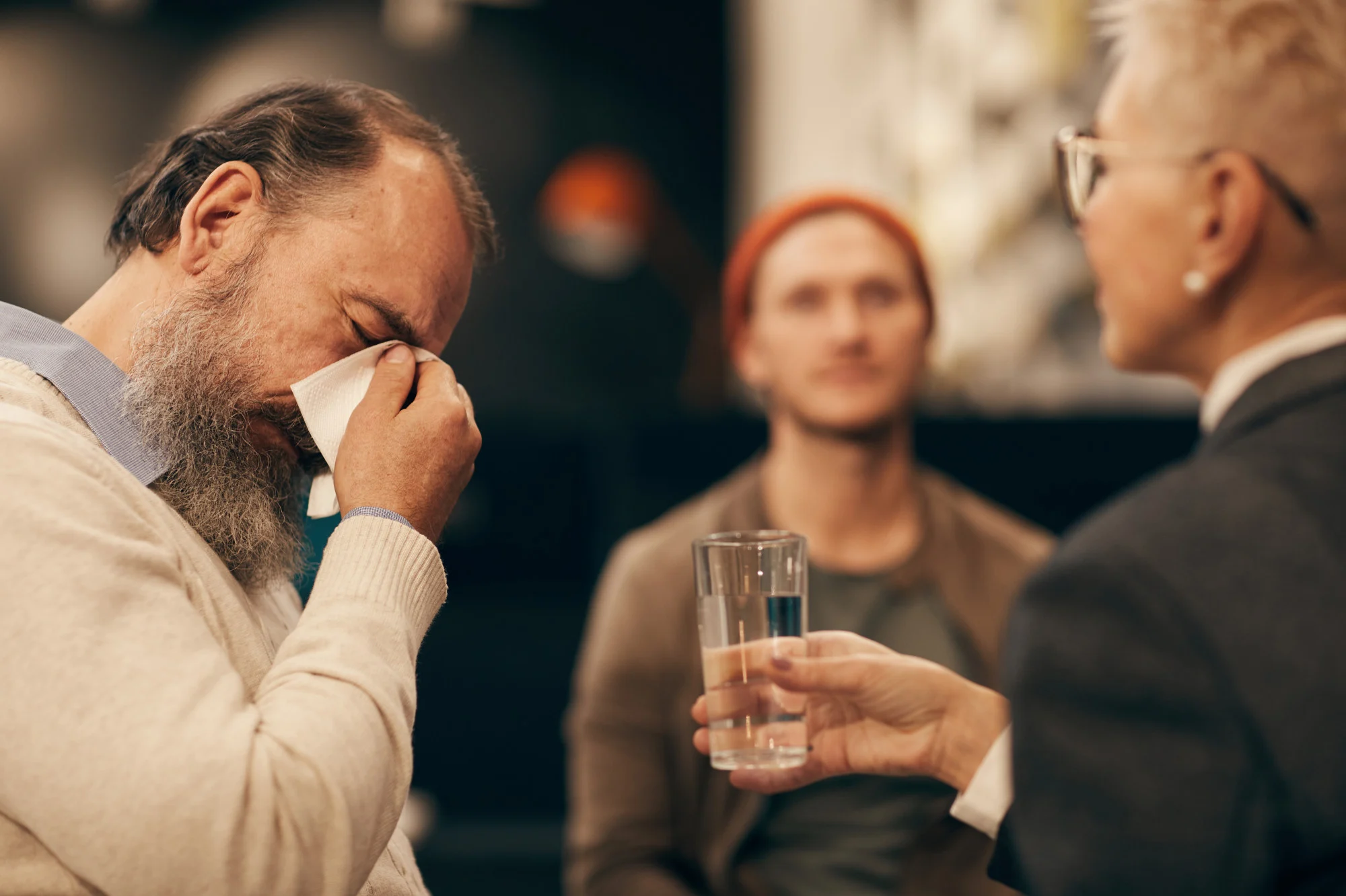 Older man wiping his eyes at a support group meeting