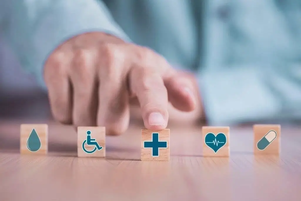 Hand arranging wooden blocks with healthcare icons