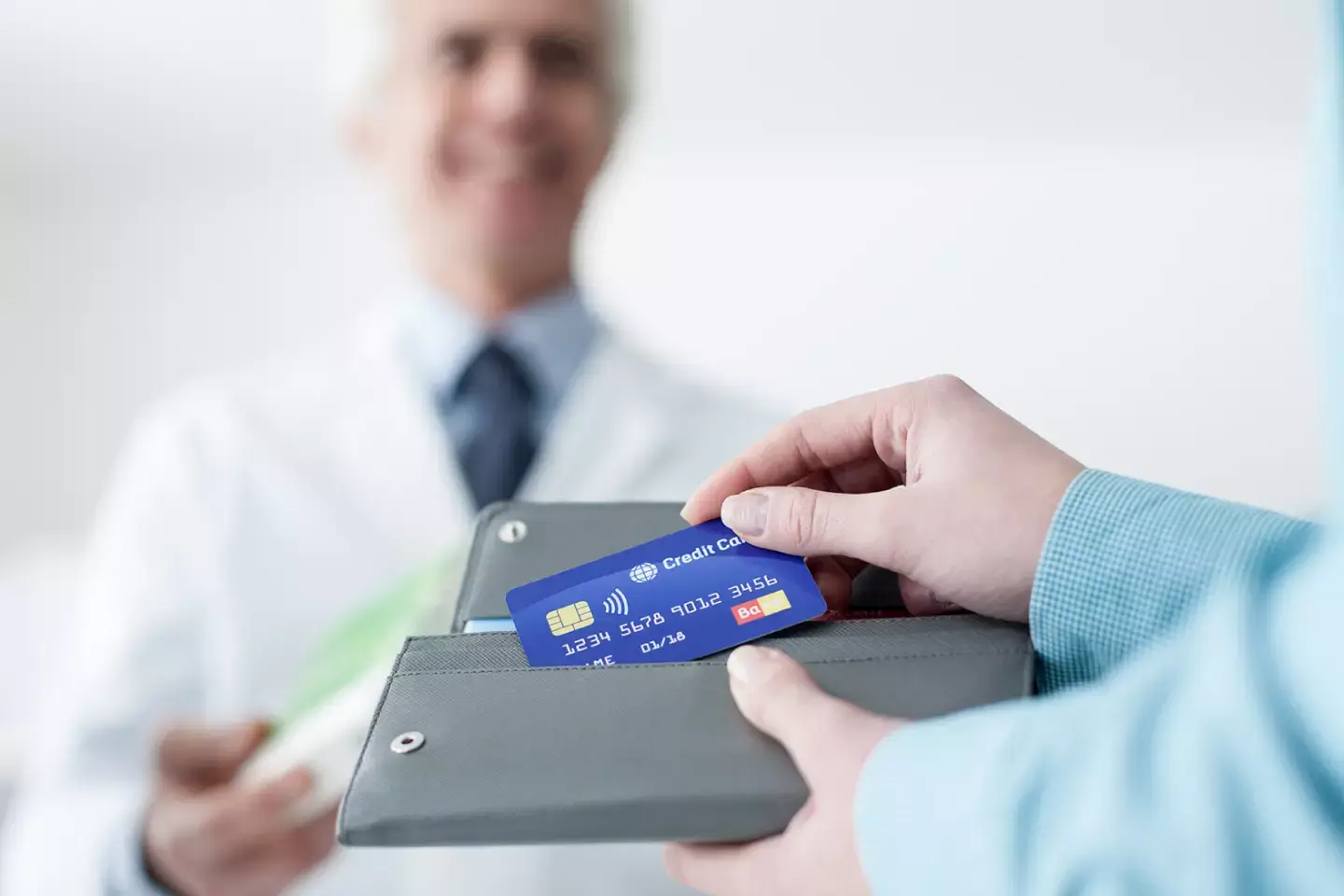 Patient handing an insurance card to a doctor