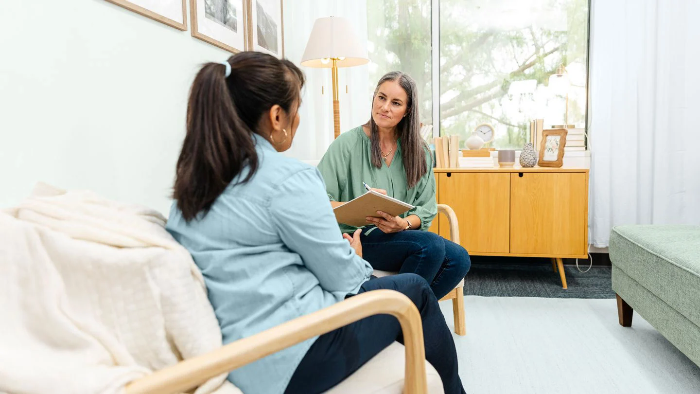Therapist reading notes to two women in a bright room