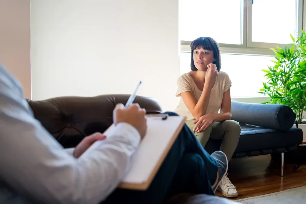 Therapist taking notes while a woman looks out the window