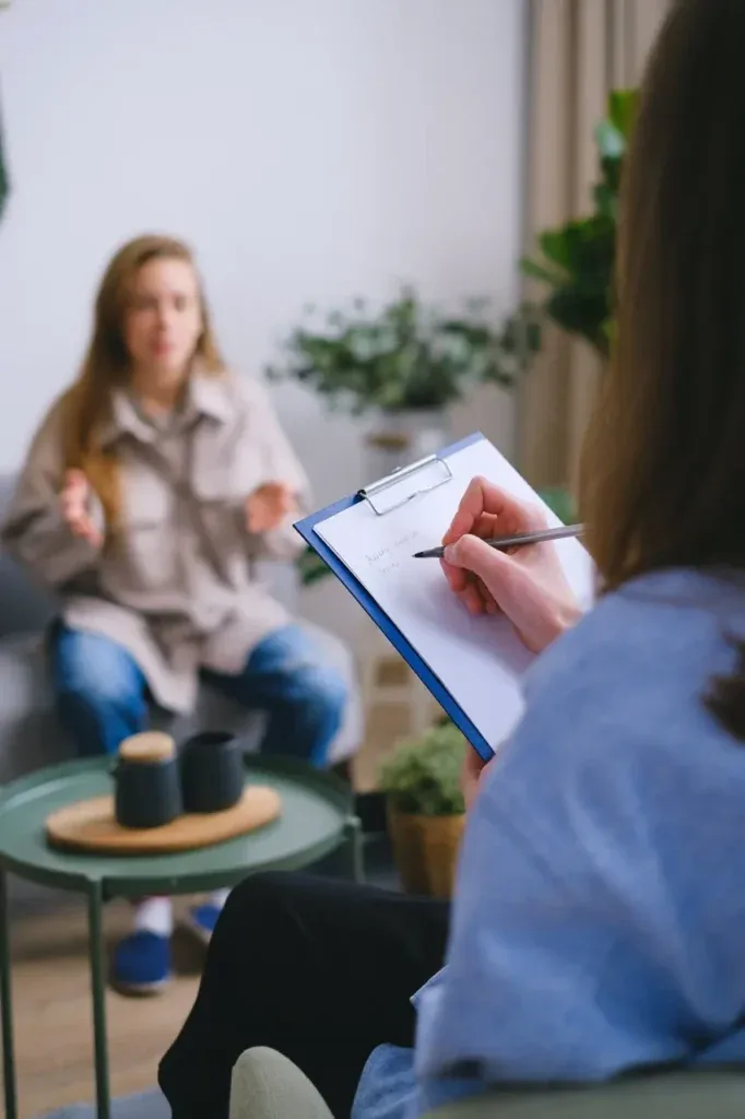 Clinician taking notes during a session with a young woman