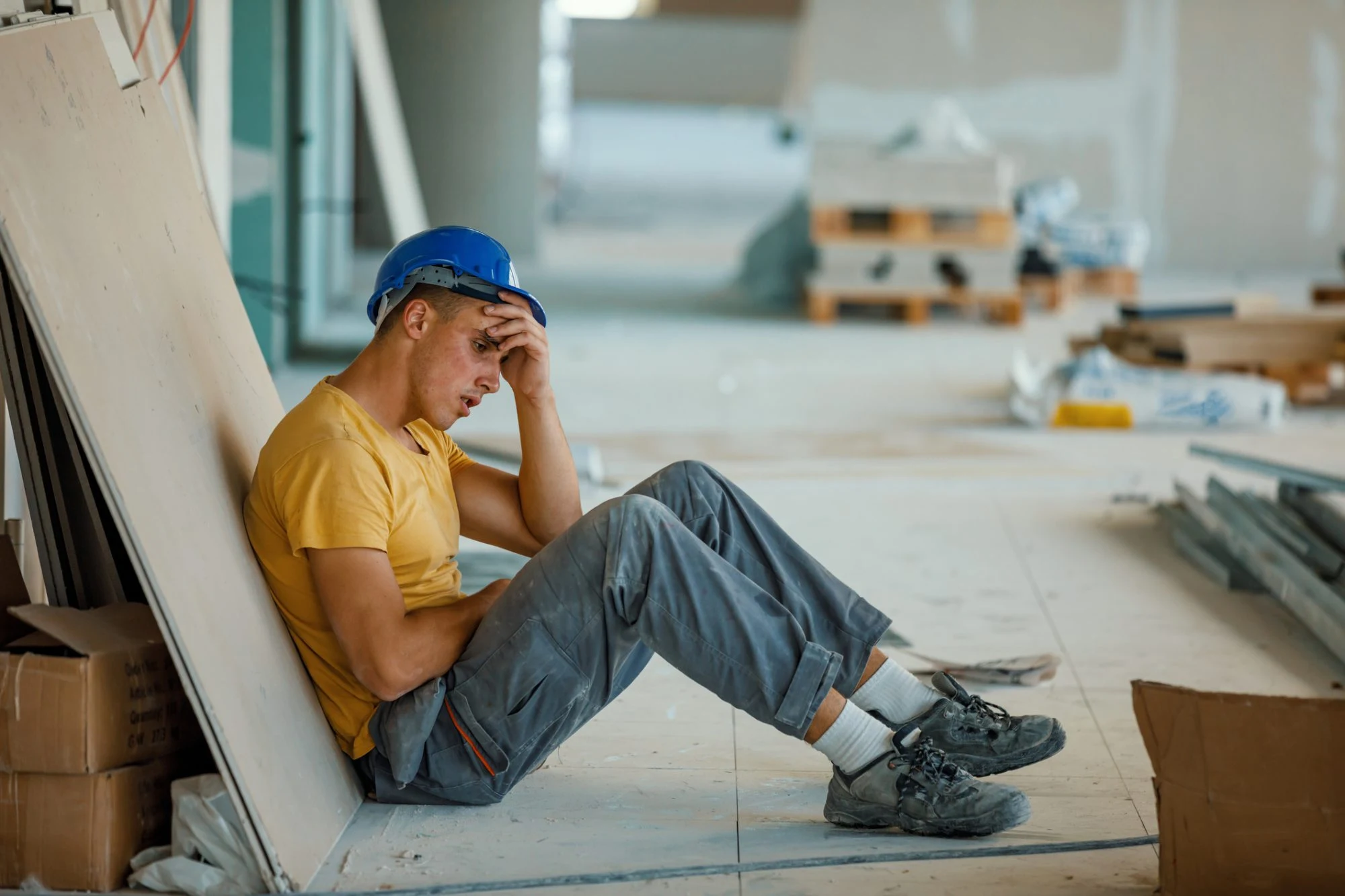 Construction worker resting against a wall on a job site
