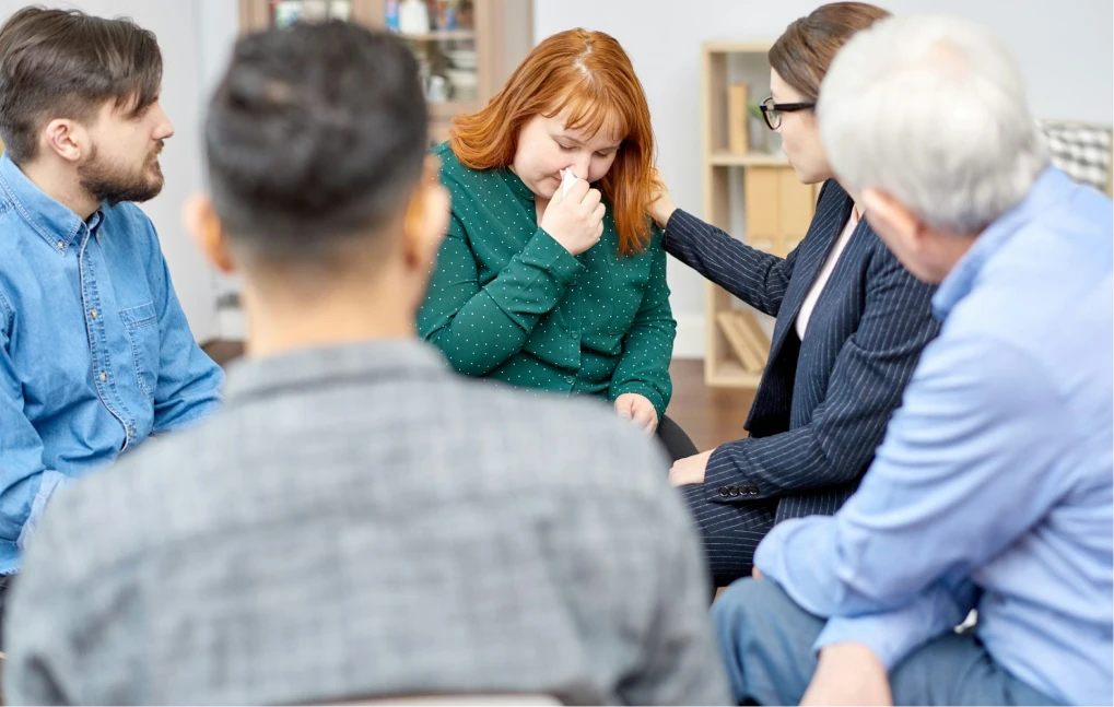 Group comforting a tearful woman during a session