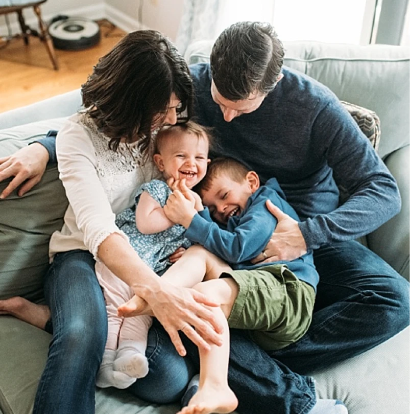 Parents playing with their two young children on a couch