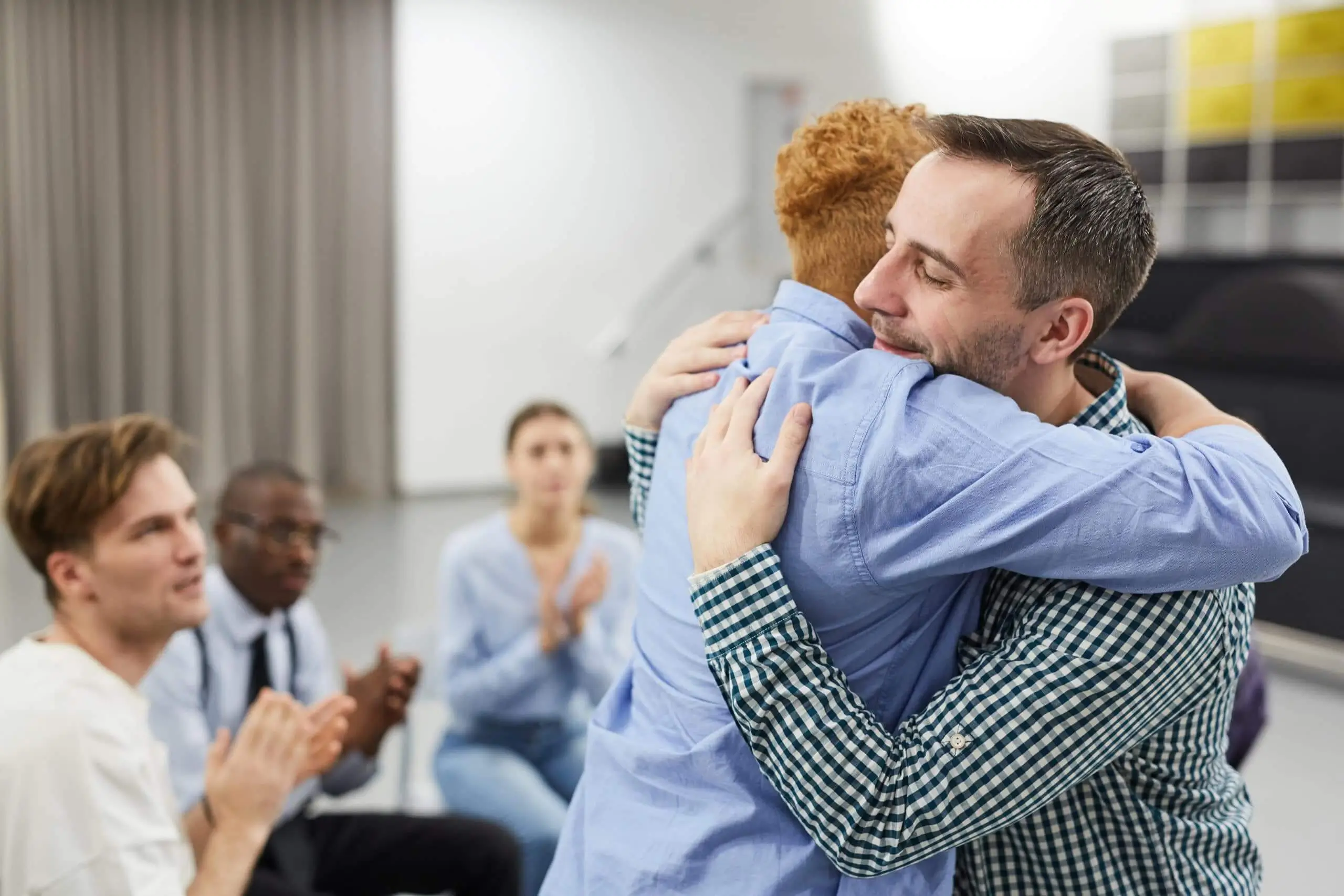 Two men hugging in support at a group meeting