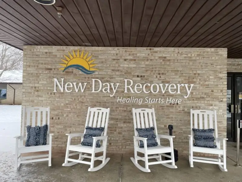 Rocking chairs on the porch beneath the New Day Recovery sign