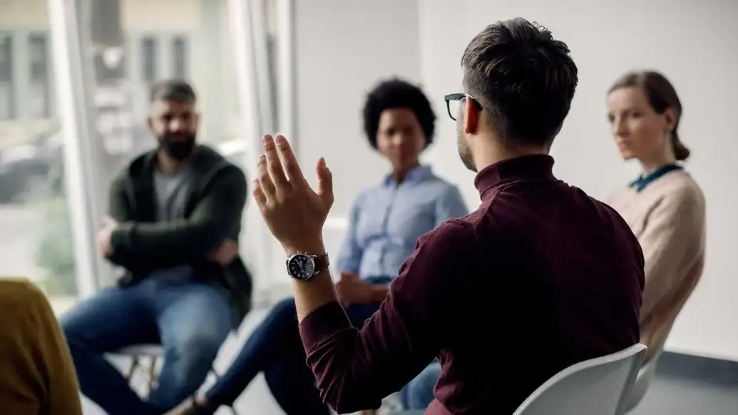 Man raising his hand in a group therapy session