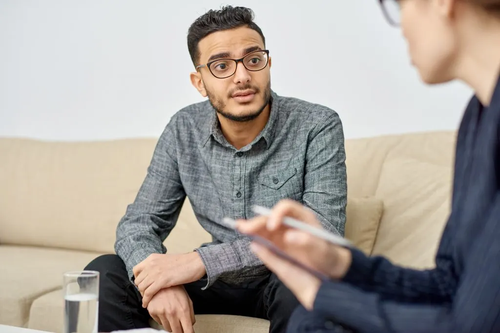 Young man talking with a counselor taking notes