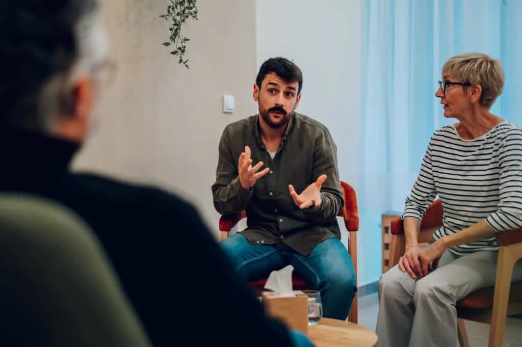 Man gesturing while speaking in a group therapy circle
