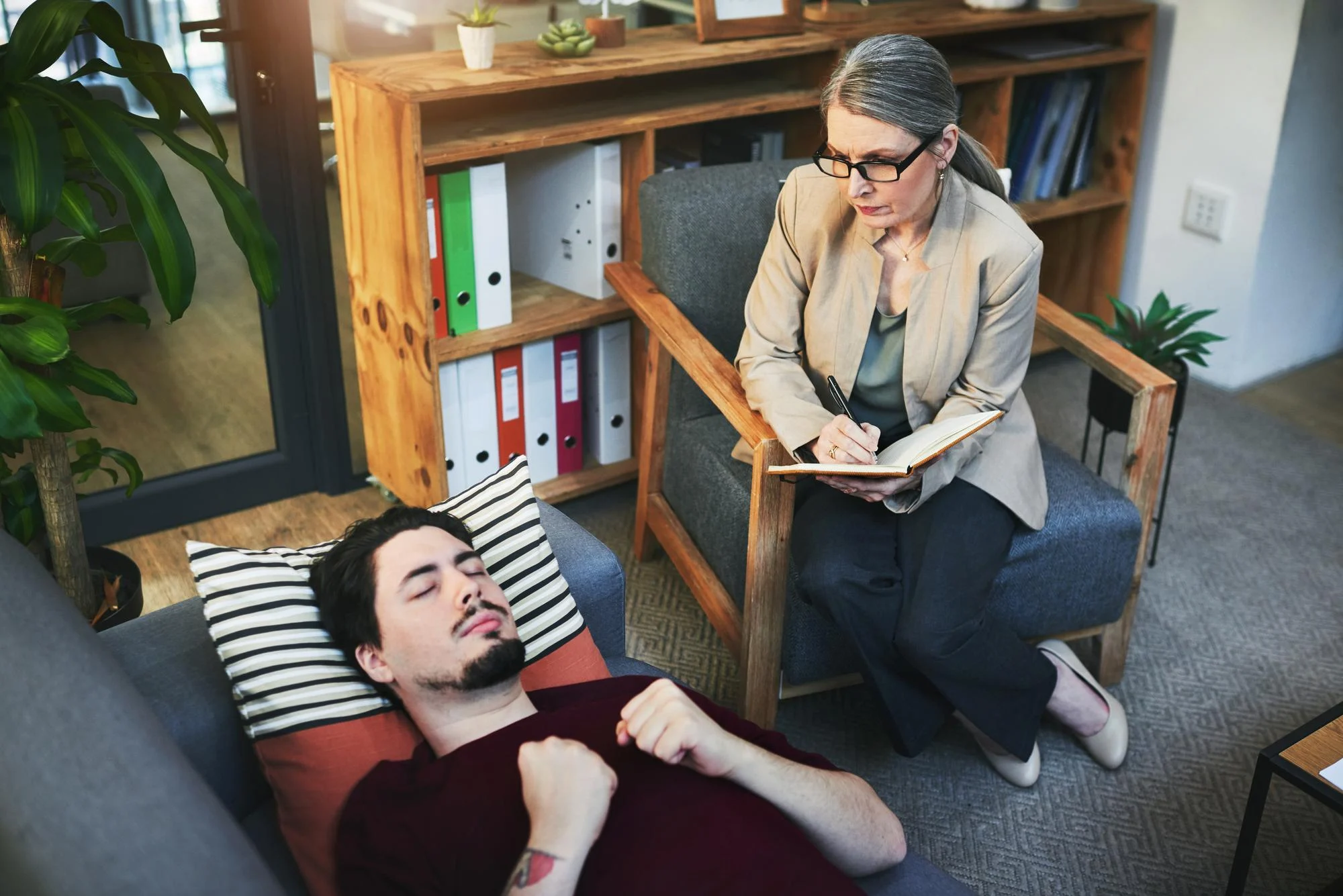 Therapists conducting a session with a man lying on a couch