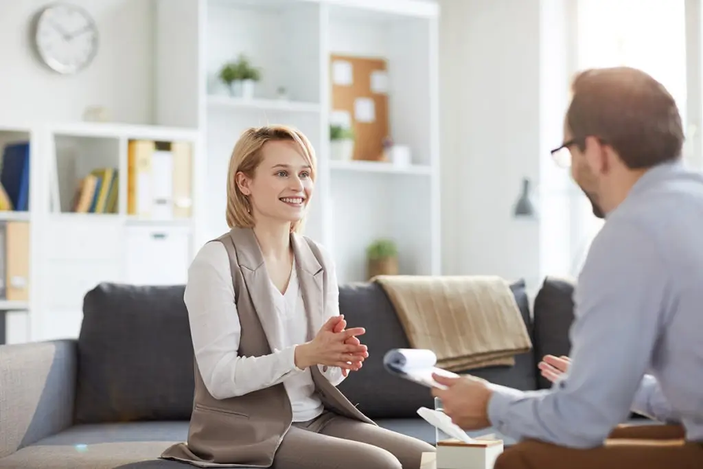 Therapist talking with a smiling woman on a couch