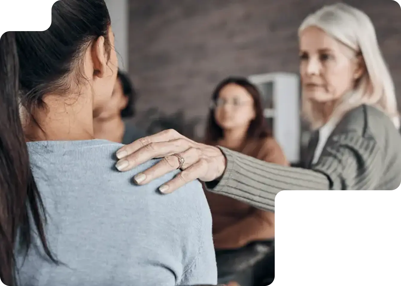 Older woman placing a comforting hand on a younger woman's shoulder