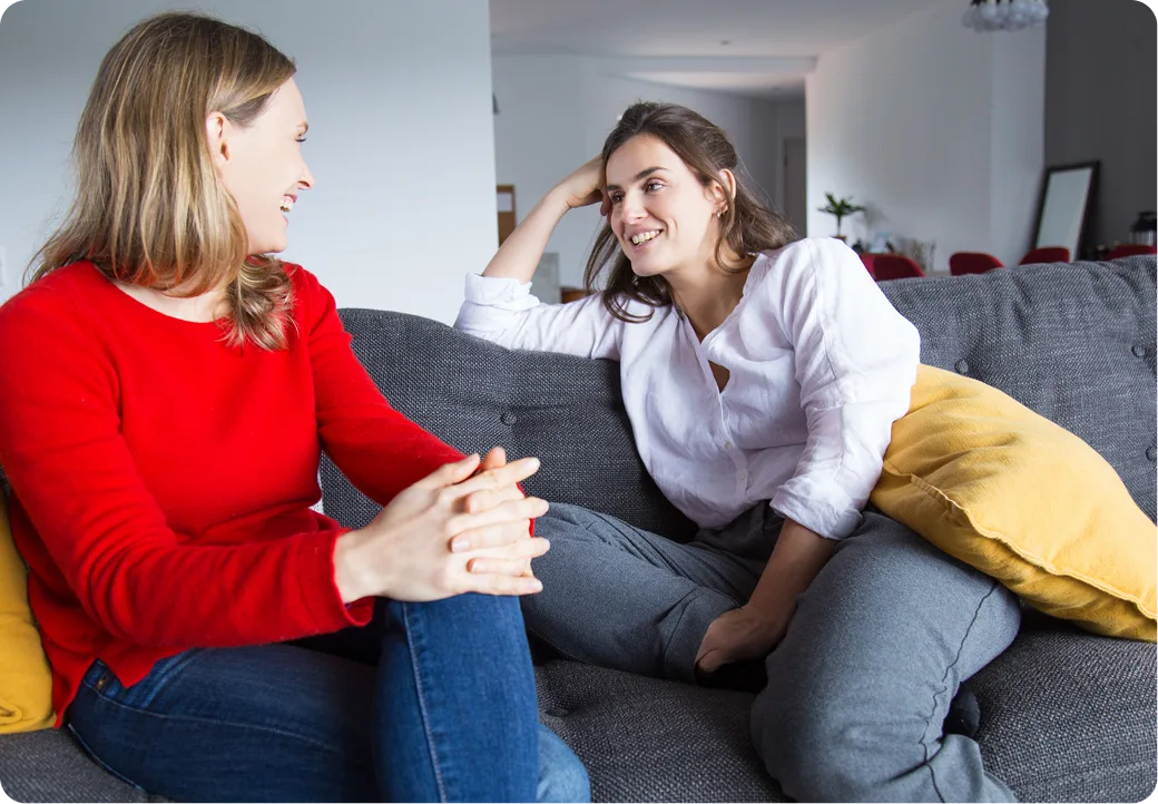 Two women laughing together on a couch