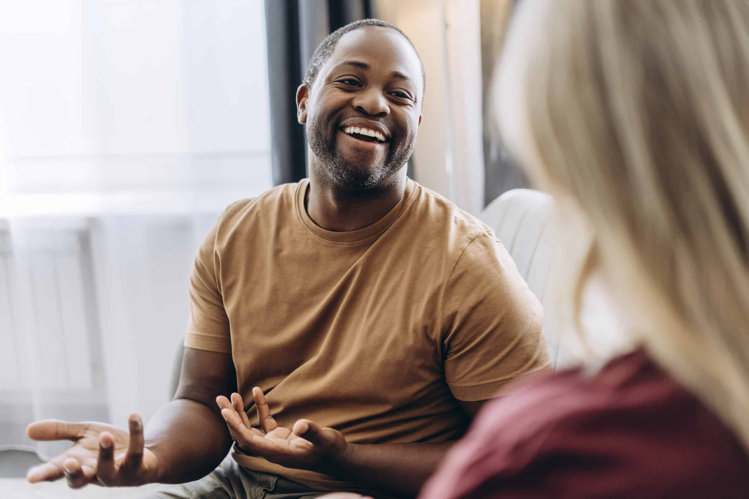 A man smiling in a therapy session while speaking about his mental health.